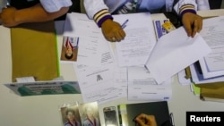 Photographs of Poowanida Kunpalin from the ruling Puea Thai Party are seen as her documents are inspected during a registration of election candidates near the Government complex in Bangkok, Thailand, Dec. 28, 2013. 