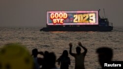 FILE - People watch the last sunset of the year from a beach on New Year's eve in Mumbai, India, December 31, 2023.