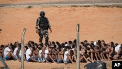 A military police officer stands next to inmates during a head count in the Alcacuz prison in Nisia Floresta, near Natal, Brazil, Jan. 24, 2017.