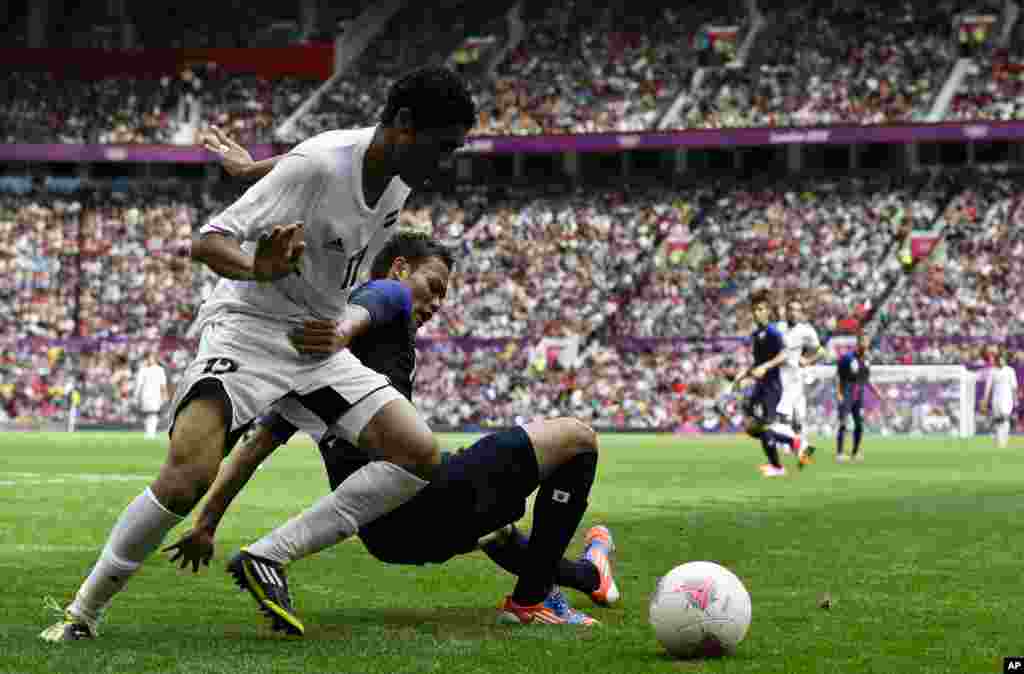 Mohamed El Neny de l&#39;Egypte, à gauche, accroché par Keigo Higashi du Japon, au centre, lors du match de football des quarts de finale entre le Japon et l&#39;Egypte dans les Jeux olympiques de 2012, le samedi 4 août 2012, à Old Trafford à Manchester, en Angleterre. (AP Photo / Ben Curtis) 