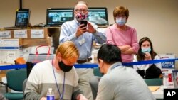 Republican canvas observer Ed White, center, and Democratic canvas observer Janne Kelhart watch as Lehigh County workers count ballots as vote counting in the general election continues, in Allentown, Pennsylvania. 