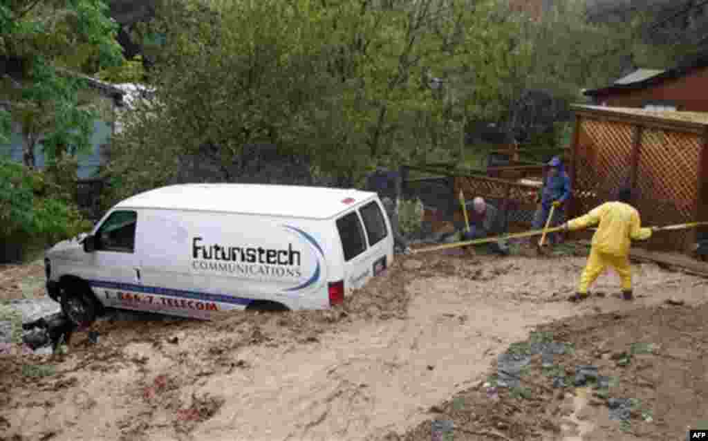 Residents tie the axle to a large tree to secure a van caught in a flooded area in Silverado Canyon, Calif., Wednesday, Dec. 22, 2010. (AP Photo/Alex Gallardo)