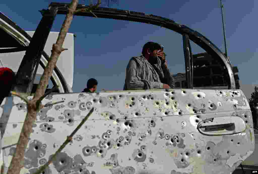 An Afghan man walks past a shrapnel-riddled car door at the scene following an explosion from a magnetic bomb attached to a civilian car in Kabul. At least two civilians were injured by the blast, officials said. 