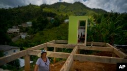 Alma Morales Rosario poses for a portrait between the beams of her home being rebuilt after it was destroyed by Hurricane Maria one year ago in the San Lorenzo neighborhood of Morovis, Puerto Rico, Sept. 8, 2018. 