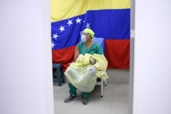 Backdropped by a national flag, a doctor waits to receive a dose of the Russian COVID-19 vaccine Sputnik V at the Ana Francisca Perez de Leon II public hospital in Caracas, Venezuela, Feb. 19, 2021.