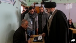 یک روحانی شیعه در انتخابات شوراهای استانی عراق رای می‌دهد.