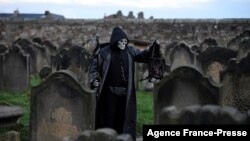 A participant in costume stands amongst gravestones at St. Mary the Virgin&#39;s church during the biannual &#39;Whitby Goth Weekend&#39; festival in Whitby, northern England.