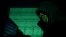 A hooded man uses a laptop as cyber code is projected on him in this illustration picture taken on May 13, 2017. 