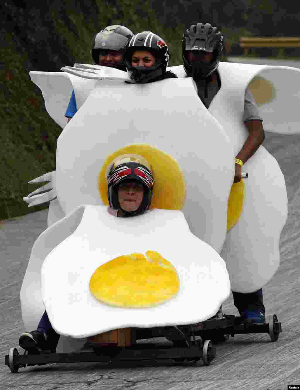 Participants wearing fried egg costumes descend down a hill in a homemade roller cart for the 24th Rollercoaster Cart Festival of Medellin, Colombia, Oct. 27, 2013. 
