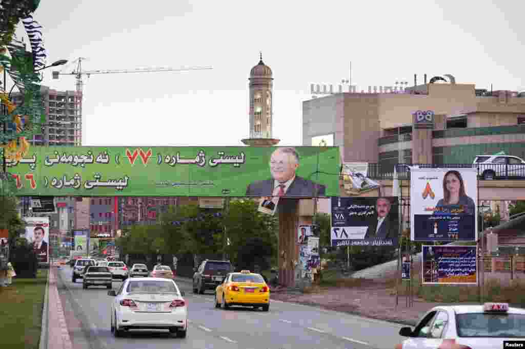 Vehicles drive under a campaign poster of Iraq's President Jalal Talabani (in green) of the Patriotic Union of Kurdistan (PUK) before the country's parliamentary elections in Sulaimaniya April 28, 2014. Picture taken April 28, 2014. To match IRAQ-E