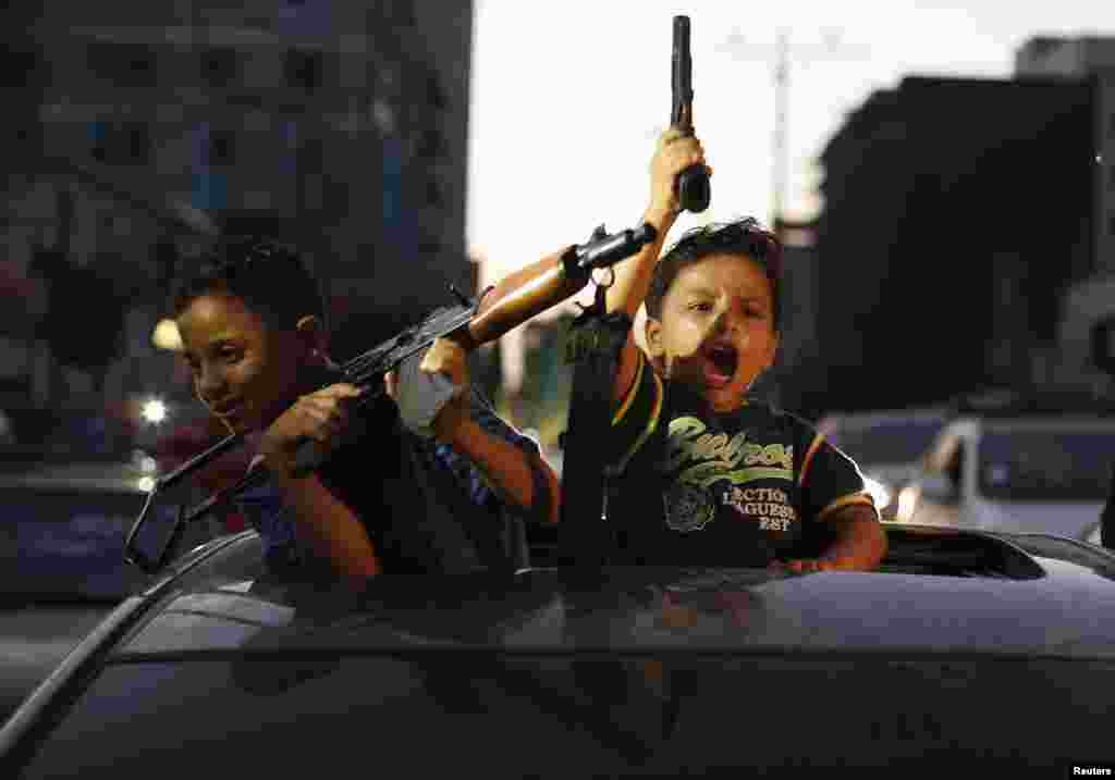 Palestinian children hold guns in Gaza City as they celebrate with others what they said was a victory over Israel, following a ceasefire. Israel has accepted an Egyptian proposal for a Gaza ceasefire, a senior Israeli official said.