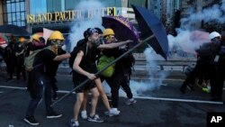 Para pengunjuk rasa menggunakan payung untuk melindungi diri dari gas air mata yang ditembakkan para polisi saat bentrok di sebuah jalan di Hong Kong, Minggu, 28 Juli 2019.