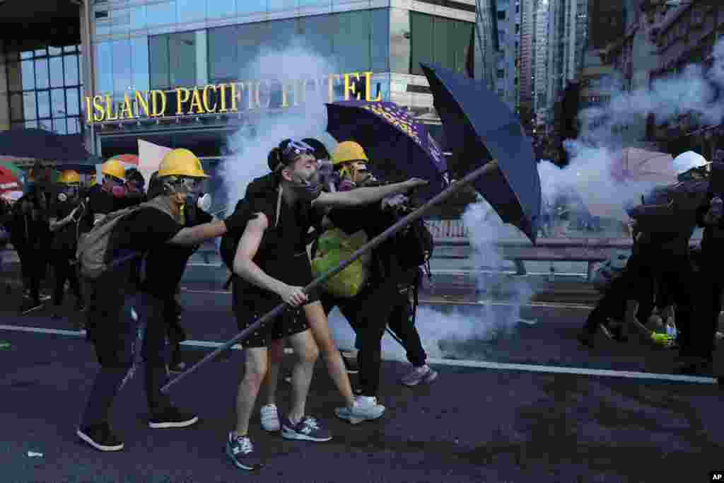 معترضان هنگ کنگی که به دخالت های چین معترض هستند، با چتر در مقابل حمله پلیس و شلیک گاز اشک آور ایستاده اند.