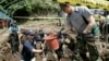 Bob Wood, Garden Valley, Calif., a members of the JPAC, Joint POW/MIA Accounting Command, second from left, deliveries a basket containing earth to South Korean Army soldiers Lee Byung-jin as he digs to search for remains of U.S. soldiers killed during the 1950-53 Korean War in Hwacheon, South Korea, May 18, 2009. 