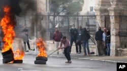 A Palestinian protester pushes a burning tire during a demonstration in the West Bank city of Bethlehem, Dec. 22, 2017.