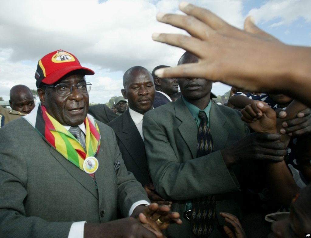 President Robert Mugabe, left, greets the crowd upon arrival at a rally in Gutu, 220 kilometers (137 miles) south of Harare, March, 17, 2005. (AP Photo)