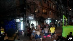 ARCHIVO - Iluminados por los faros de una motocicleta, jóvenes realizan un baile callejero conocido como passinho en la favela Rocinha de Río de Janeiro, Brasil, el 11 de abril de 2024.