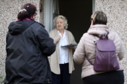 Volunteers hand out the COVID-19 home test kit to a resident, in Goldsworth and St. Johns, amid the outbreak of coronavirus disease in Woking, Britain, Feb. 2, 2021.