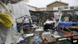 Residentes caminan junto a los destrozados puestos de un mercado público tras el paso del tifón Mangkhut por la ciudad de Tuguegrao, en la provincia de Cagayan, en el noreste de Filipinas (AP Foto/Aaron Favila)