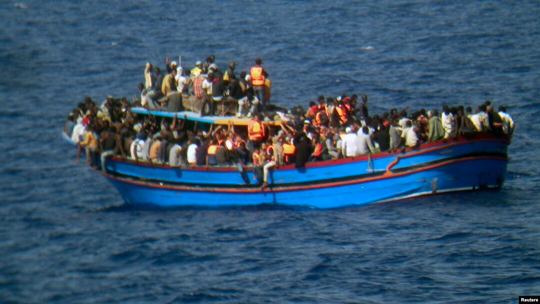 Migrants sit in their boat during a rescue operation by Italian navy ship Grecale (not pictured) off the coast of Sicily, in this handout picture by the Italian Marina Militare, June 29, 2014.