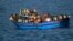 Migrants sit in their boat during a rescue operation by Italian navy ship Grecale (not pictured) off the coast of Sicily, in this handout picture by the Italian Marina Militare, June 29, 2014.