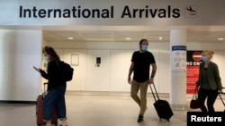 Passengers are seen wearing face coverings after arriving at Manchester Airport following the outbreak of the coronavirus disease (COVID-19) in Manchester, Britain, July 26, 2020. 