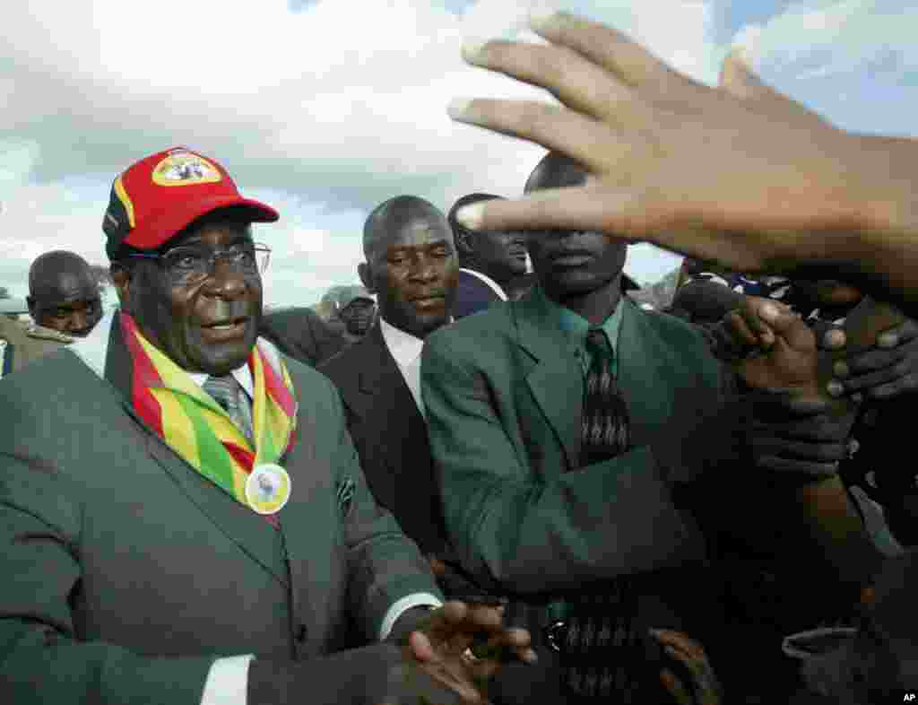 Presiden Robert Mugabe, kiri, menyapa kerumunan massa saat tiba di pertemuan umum di Gutu Gutu, 220 km (137 mil) selatan Harare, 17 Maret 2005. (AP Photo)