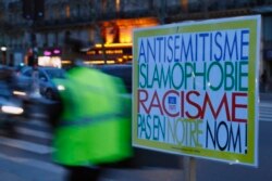 A poster reading "Anti-Semitism, Islamophobia, Racism, Not in Our Name" during a gathering decrying anti-Semitism at Place de la Republique in Paris, Feb. 18, 2019.