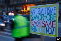 A poster reading "Anti-Semitism, Islamophobia, Racism, Not in Our Name" during a gathering decrying anti-Semitism at Place de la Republique in Paris, Feb. 18, 2019.