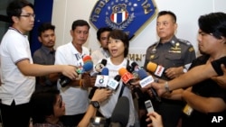 Police Lt. Gen. Thitiraj Nhongharnpitak, second right, watches Noppawan "Ploy" Bunluesilp, center, wife of British journalist Andrew McGregor Marshall, address the media as she prepares to leave a Bangkok police station on July 22, 2016.