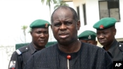 Diepreye Alamieyeseigha, centre, stands outside his house guarded by policemen in Yenagoa, Nigeria, in this file photo dated November 27, 2005.