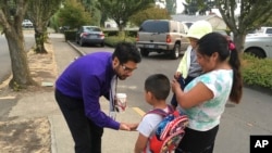 Oscar Belanger, assistant principal of Nellie Muir Elementary School, in Woodburn, Oregon, where 82 percent of students are Latino, slaps five with a student arriving for the first day of class on Tuesday, Sept. 5, 2017. 