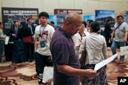 A Chinese man looks at a leaflet at exhibitor booths in a Invest in America Summit, a day after an event promoting EB-5 investment in a Kushner Companies development in Beijing, May 7, 2017.