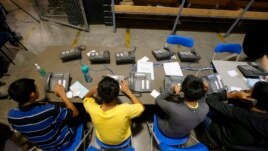 Niños aprehendidos en Arizona tratan de hacer llamadas telefónicas para comunicarse con sus familiares.