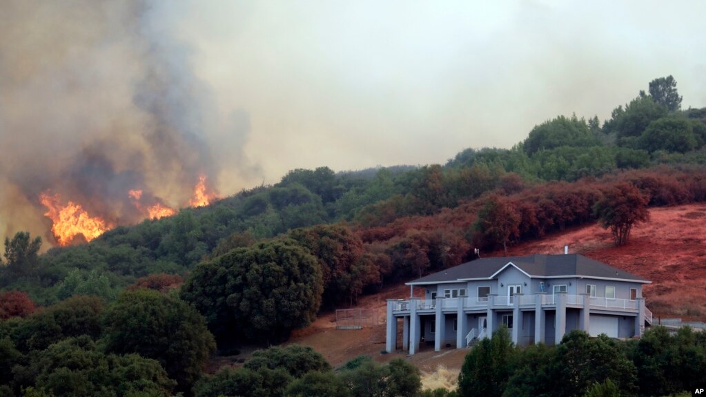 Las llamas de un incendio amenazan un casa en Lakeport, California, el lunes, 30 de julio de 2018.