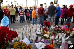 People pray at a makeshift memorial to honor the victims of Wednesday's shooting rampage, Dec. 5, 2015, in San Bernardino, Calif.