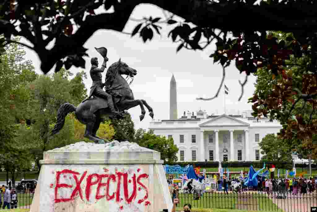 The words &quot;Expect Us&quot; are spray-painted on the base of the Andrew Jackson statue in Lafayette Park as Indigenous and environmental activists protest in front of the White House in Washington.