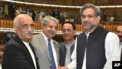 Newly-elected Prime Minister of Pakistan Shahid Khaqan Abbasi, right, is greeted by the Opposition leader Khursheed Shah, left, and others at the Parliament in Islamabad, Pakistan, Tuesday, Aug. 1, 2017. 