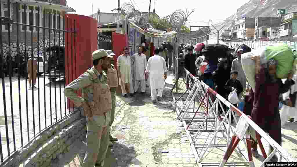 On the right, people going to Afghanistan. On the left, Pakistani security personnel watching.