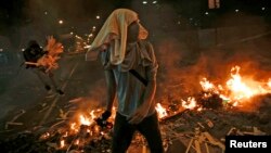 Opposition supporters walk past a burning barricade at Altamira square in Caracas, Feb. 20, 2014.