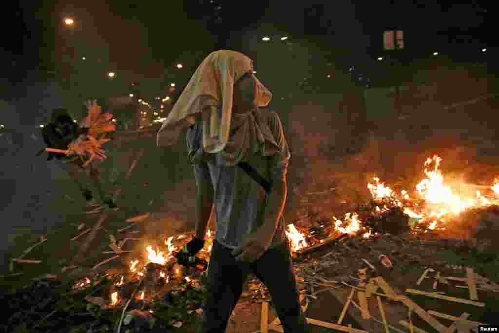 Opposition supporters walk past a burning barricade at Altamira square in Caracas, Feb. 20, 2014.