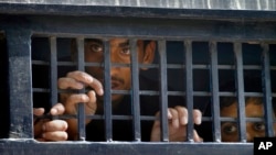 FILE - Detainees peer out from a prison van after their court appearance in Islamabad, Pakistan, Sept. 13, 2014. 