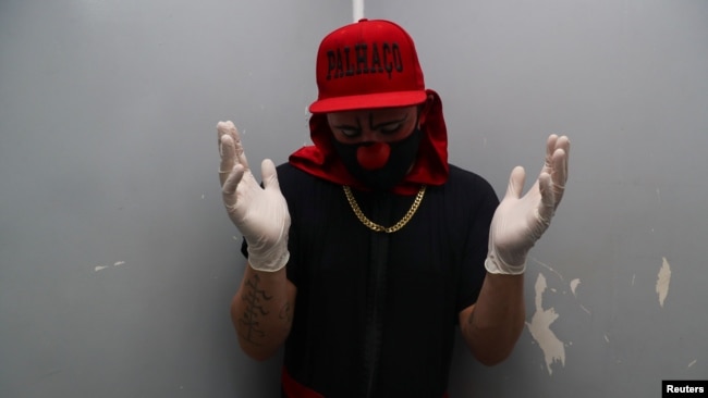 Flavio Falcone, a psychiatrist, wears gloves and a protective face mask in the elevator of the building where he lives as he makes his way to perform as a clown in an area known as "cracolandia," or crackland in Sao Paolo, Brazil. REUTERS/Amanda Perobelli