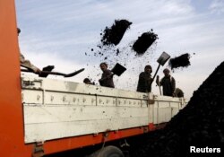 FILE - Laborers unload coal from a truck at a coal dump site in Kabul, Afghanistan, Nov. 19, 2015.
