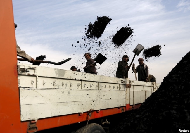 FILE - Laborers unload coal from a truck at a coal dump site in Kabul, Afghanistan, Nov. 19, 2015.