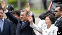 FILE - South Korea's new President Moon Jae-in waves to neighborhoods and supporters with his wife Kim Jung-sook upon their arrival outside the presidential Blue House in Seoul, South Korea, May 10, 2017.