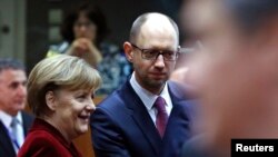 FILE - German Chancellor Angela Merkel (L) is seen with Ukraine's Prime Minister Arseniy Yatsenyuk (C) during a European leader emergency meeting on Ukraine, in Brussels March 6, 2014.