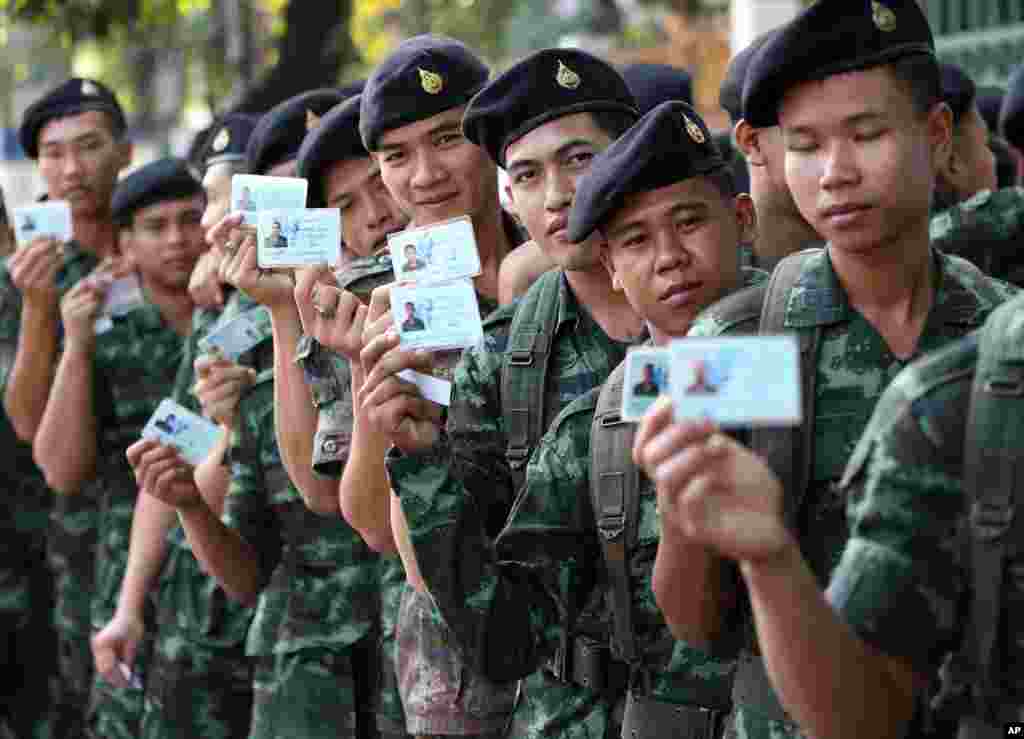 Thai soldiers pose with their identity cards as they wait in a line to vote at a polling station in Bangkok, Feb. 2, 2014. 