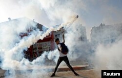Seorang demonstran mengembalikan tabung gas air mata selama protes atas keputusan AS atas pemukiman Yahudi, di dekat pemukiman Yahudi Beit El di Tepi Barat yang diduduki Israel, 26 November 2019. (Foto: REUTERS/ Mohammad Torokman)