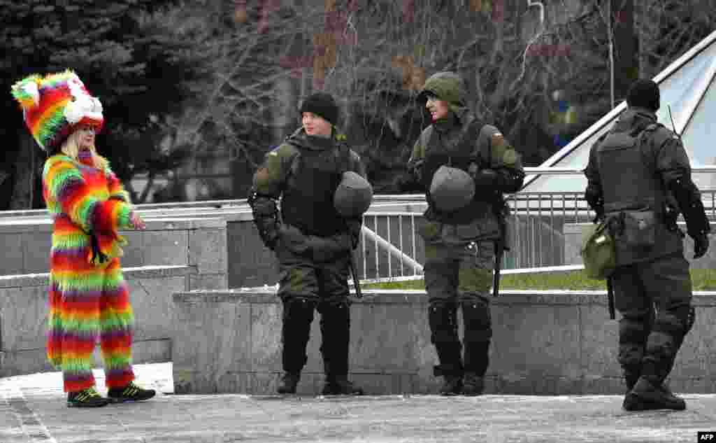 Ukrainian National Guard members walk past a woman wearing a colorful costume as they patrol near Independence Square in Kiev following a night of violence by activists of some far-right parties.